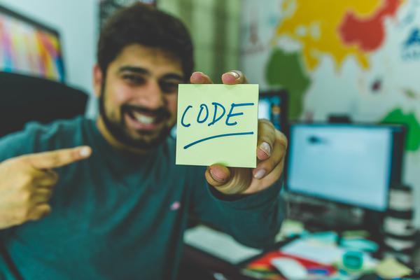 guy holding post-it note that says 'Code' because he loves javascript and other programming languages