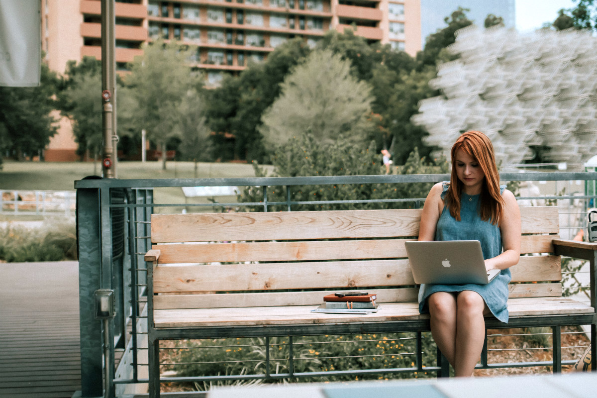 Woman using her laptop in a park, planning a career change Woman using her laptop in a park, planning a career change