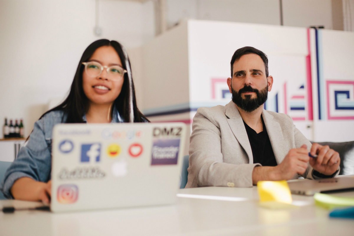 Two developers a with laptops listening, representing getting jobs after bootcamp Two developers a with laptops listening, representing getting jobs after bootcamp